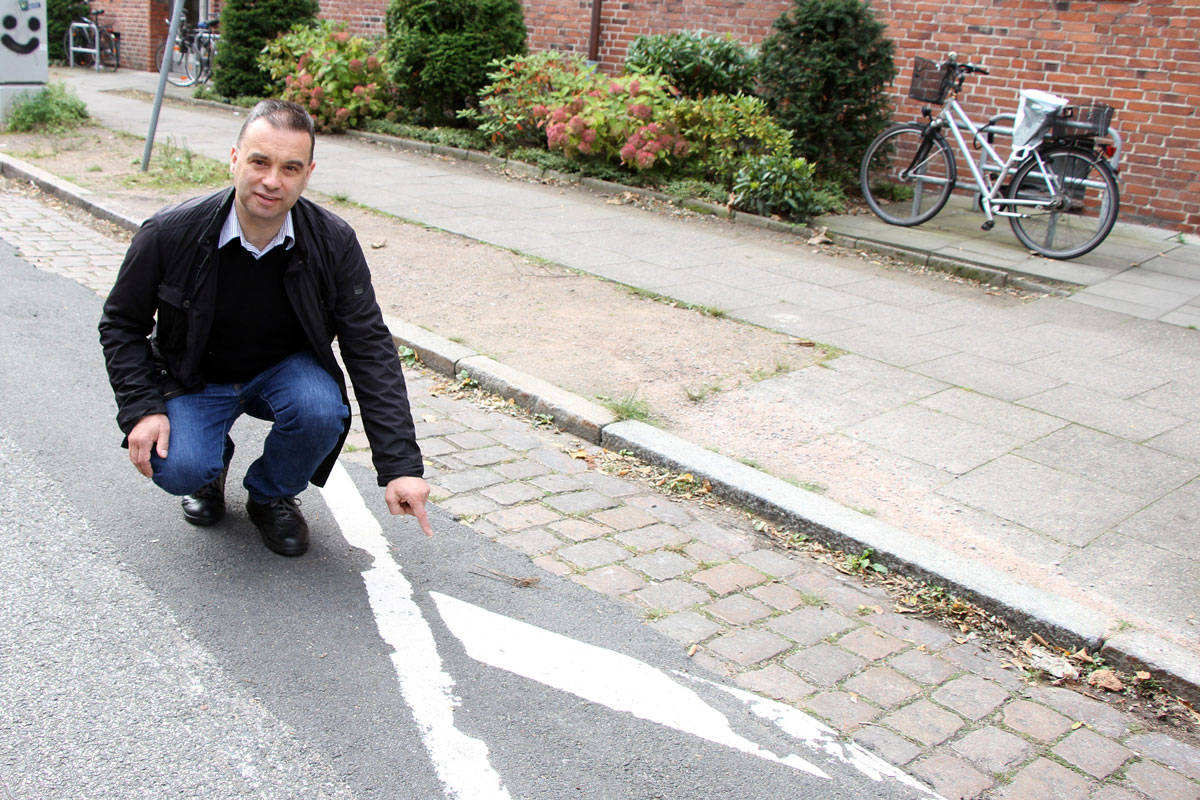 CDU-Bezirksabgeordneter Stefan Baumann zeigt die abgenutzte Farbmarkierung an der Heitmannstraße.