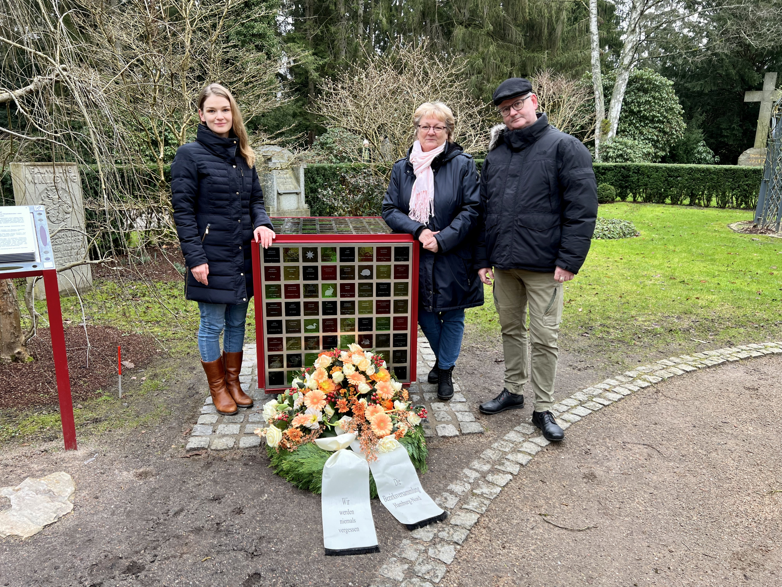 Von links: Isabel Permien (GRÜNE), Martina Lütjens (CDU) und Thomas Domres (SPD) am Gedenkwürfel für die verstorbenen Säuglinge und Kleinkinder von Zwangsarbeiterinnen auf dem Friedhof Ohlsdorf im „Garten der Frauen“. Sie legten einen Kranz zum Gedenken der Opfer in der NS-Zeit nieder.